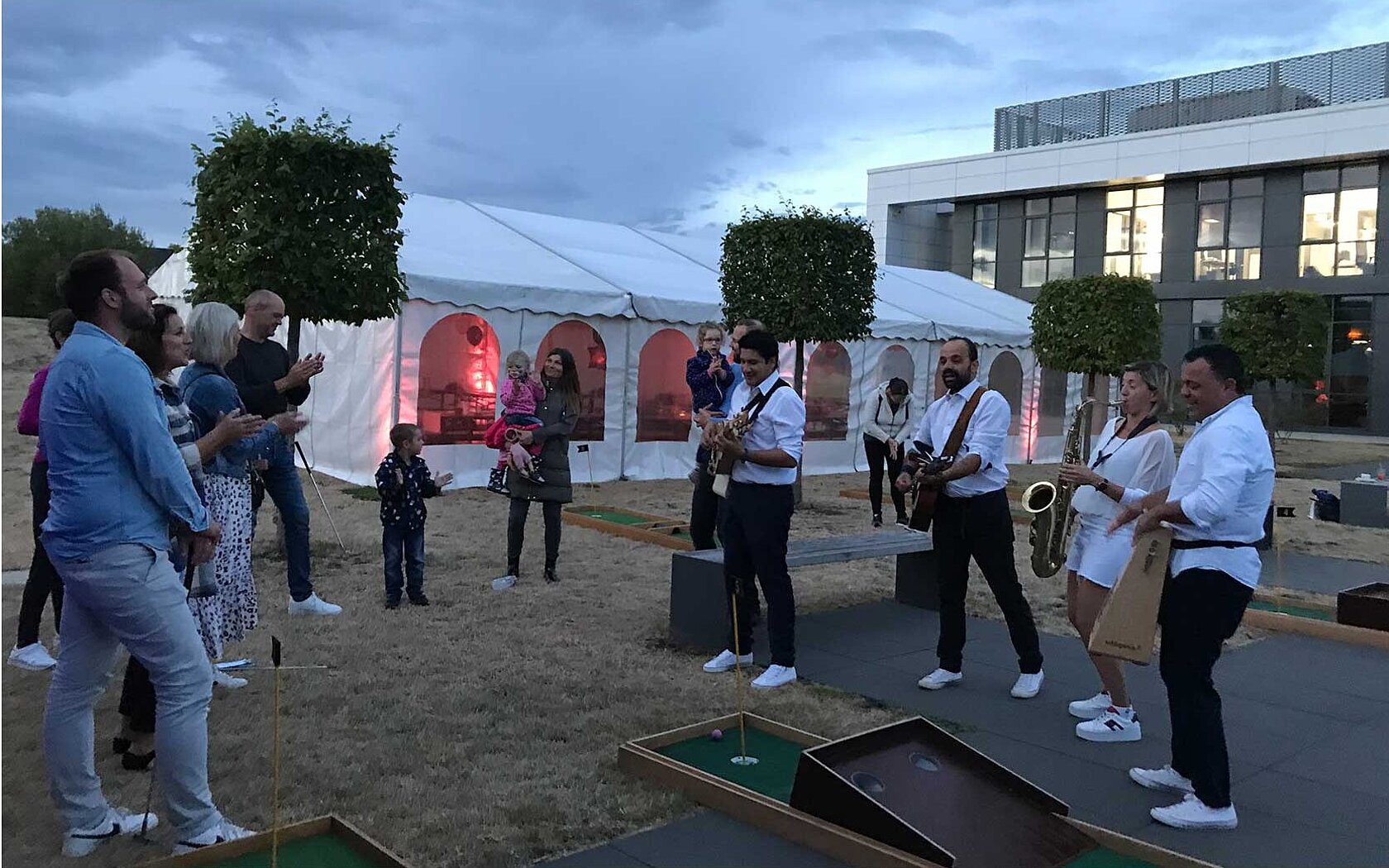 Eine Band + andere Menschen stehen vor einer beleuchteten Wand