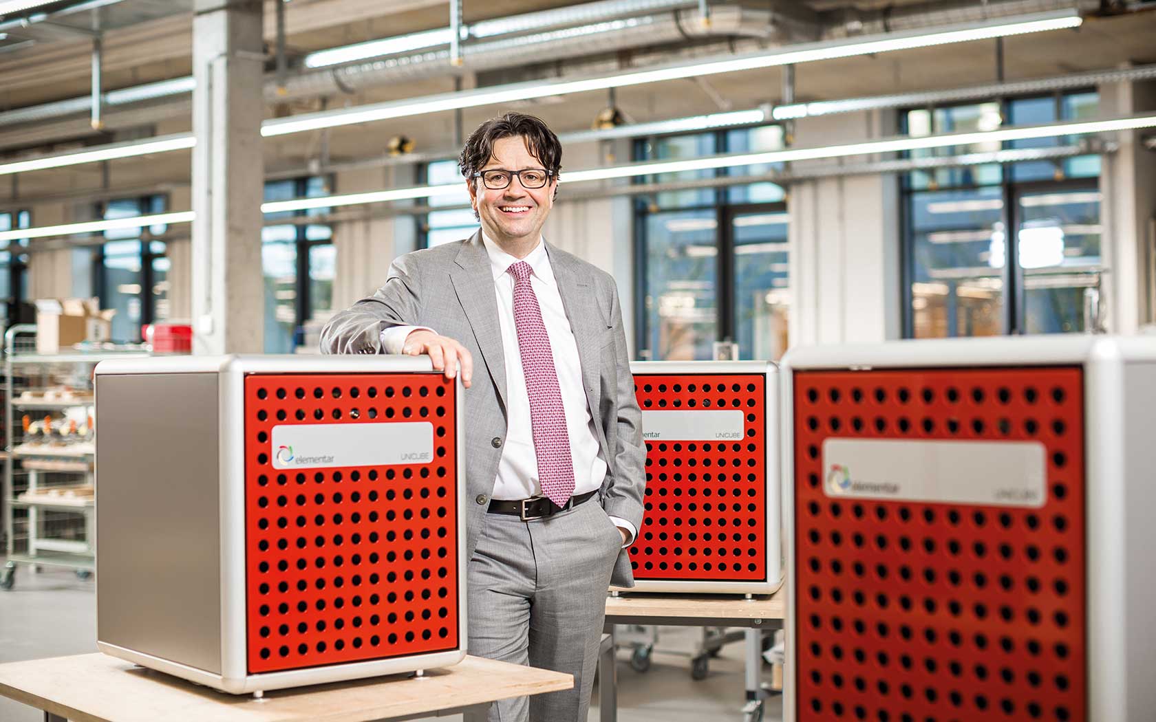 Albrecht Sieper in the production department beside three red UNICUBE elemental analyzers